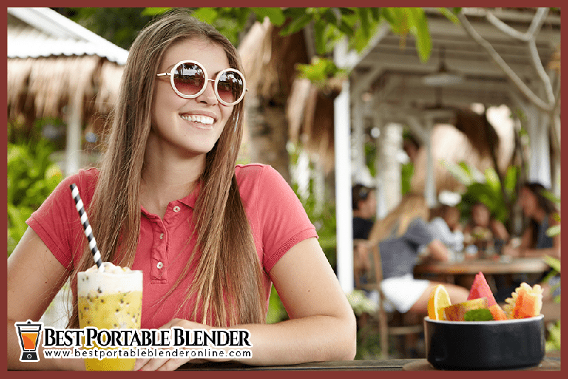 girl-enjoying-tropical-smoothie-in-a-restaurant-best-portable-blender-online